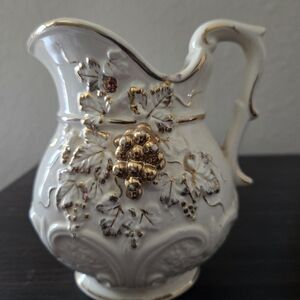 Vintage porcelain creamer pitcher featuring a raised grape and leaf design